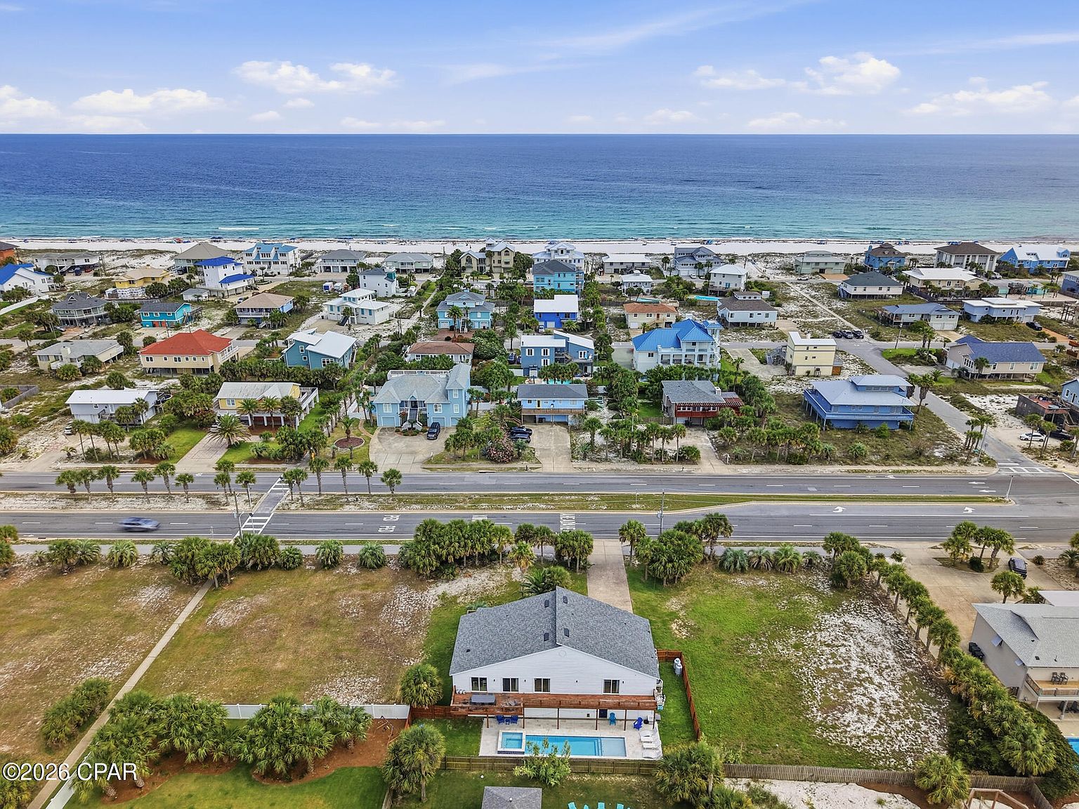 Aerial over 1205 Via De Luna Dr showing the home and pool with the Pensacola Beach community and the Gulf of Mexico beyond
